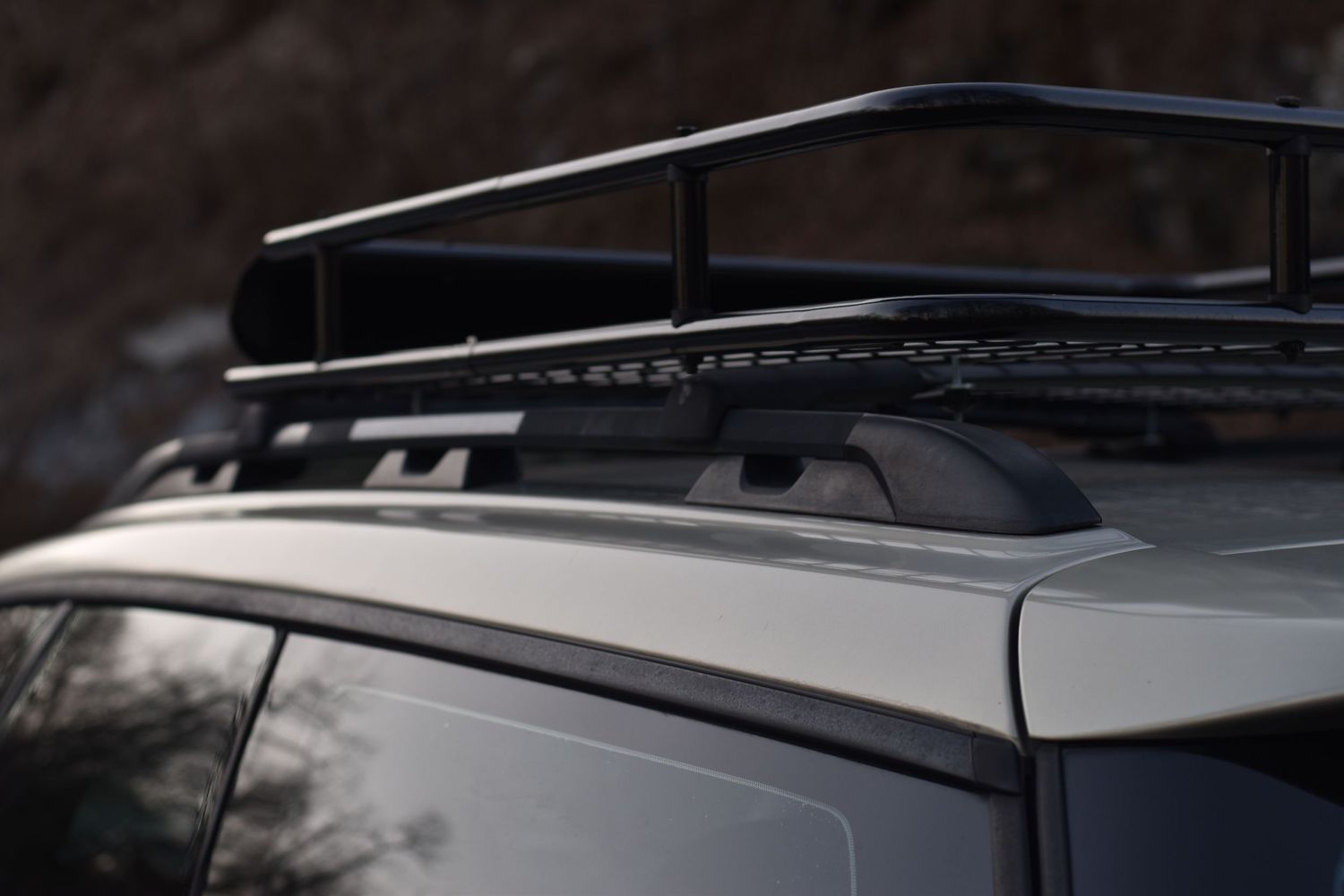 Close-up of a black Jeep's roof rack and rails against a dark background.