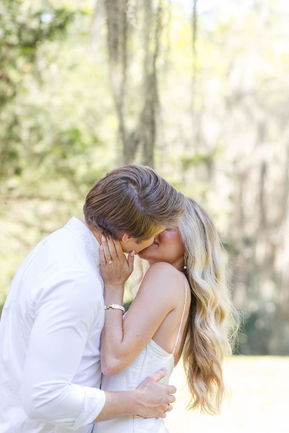Romantic embrace captured in soft sunlit outdoor setting.