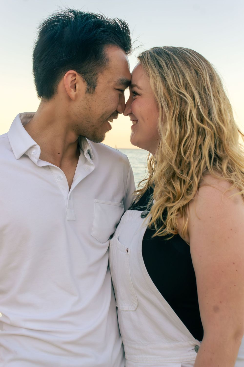 An intimate moment between a couple against an ocean backdrop at sunset.