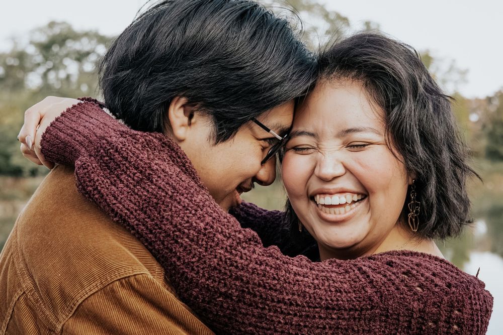 Romantic couple in burgundy and brown sweaters embrace outdoors during autumn.
