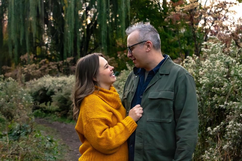Couple in autumn outfits sharing intimate moments outdoors with yellow and green foliage.