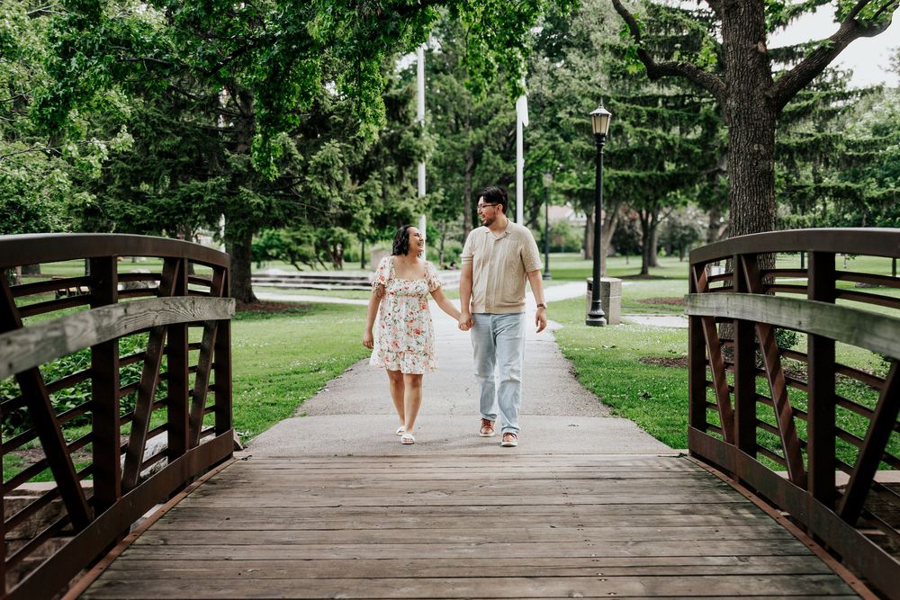 A couple walking together on a wooden bridge pathway surrounded by lush greenery.