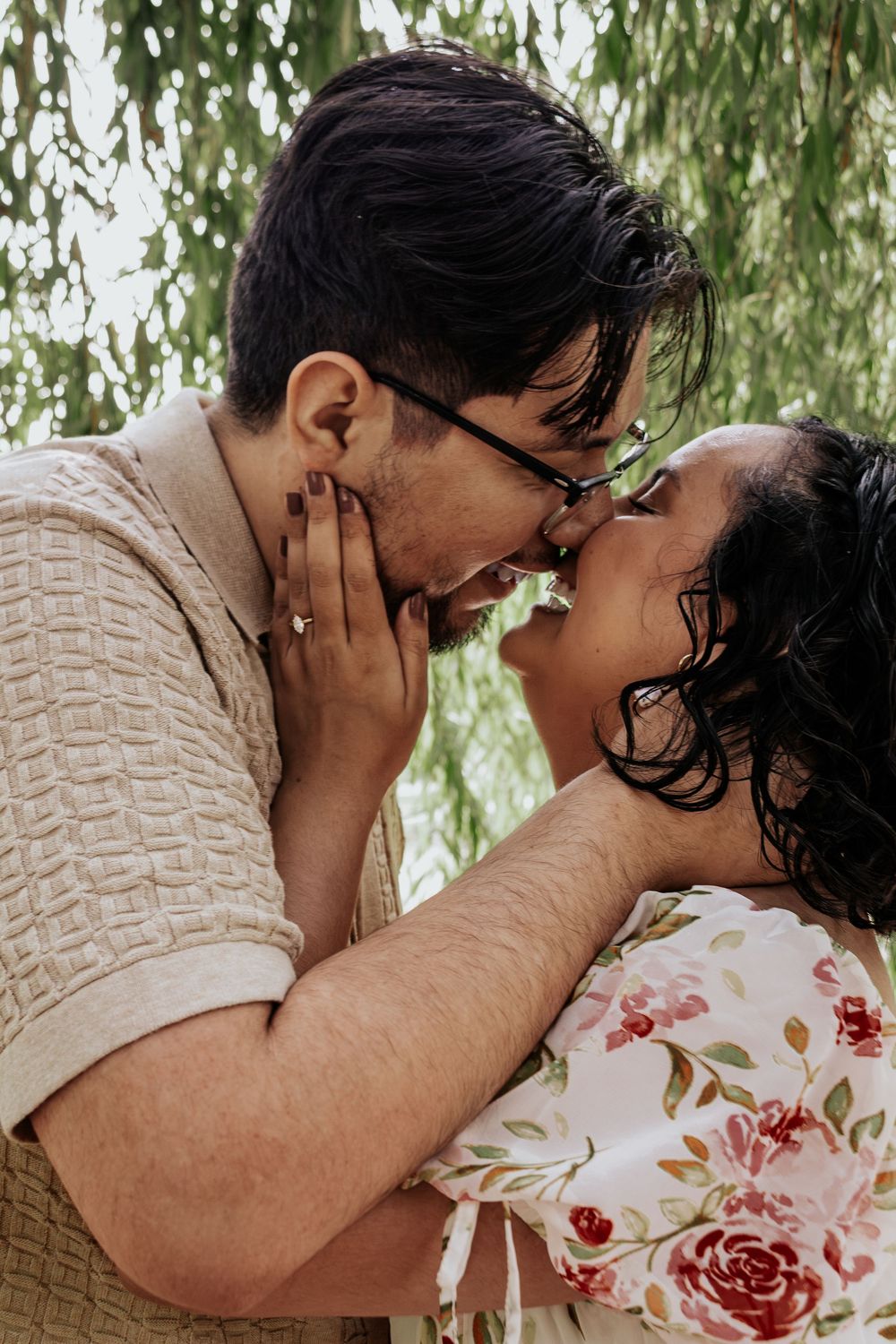 A romantic couple sharing an intimate moment under a willow tree.