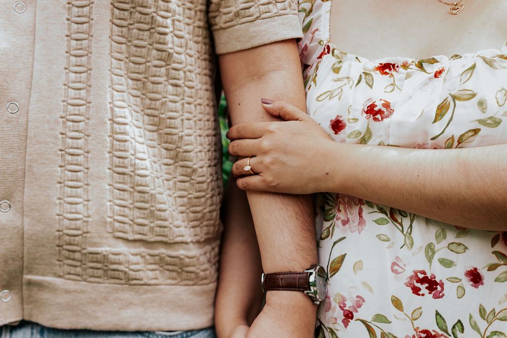 A couple holding hands with one wearing a floral dress and the other in a textured top.