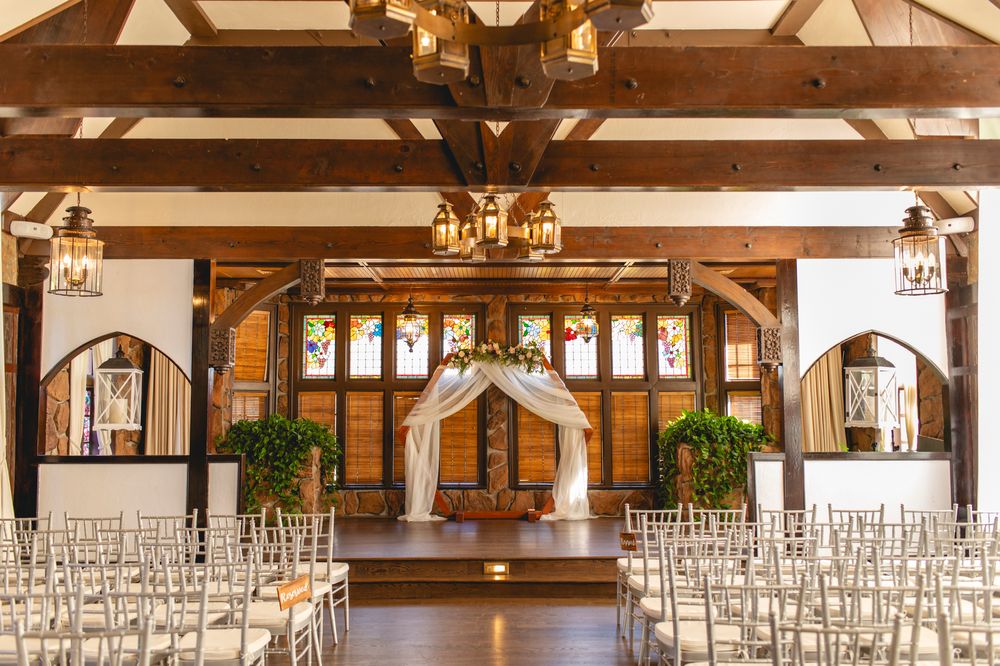 A beautiful wedding ceremony venue with wooden beams, white chairs and elegant chandeliers in a chapel-style setting.