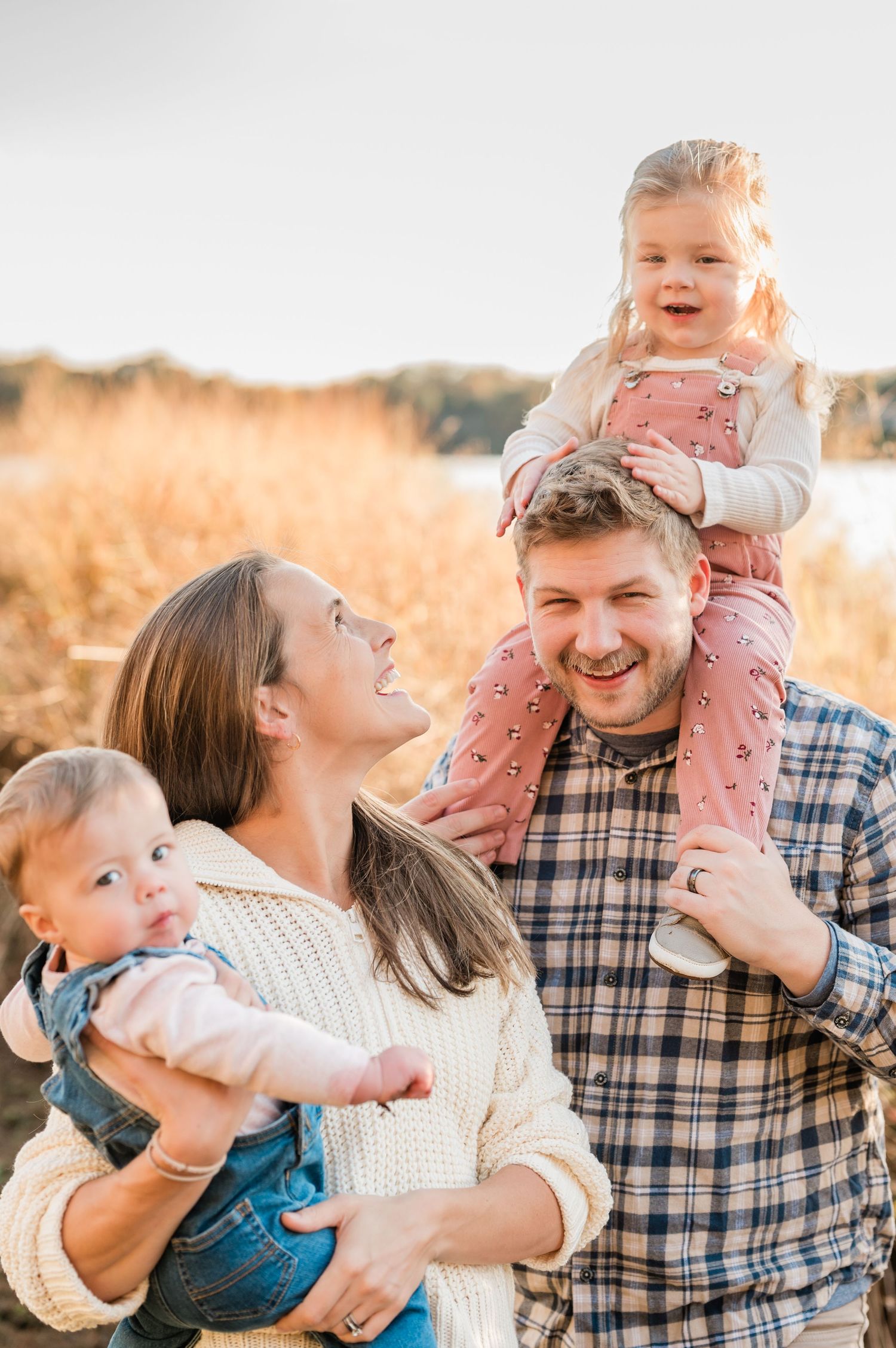 Joyful family laughing and playing together outdoors during golden hour in a field.
