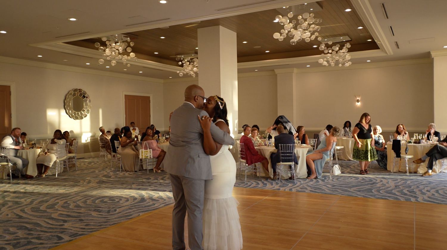 Wedding reception ballroom with couples dancing on the floor and elegant ceiling decorations.