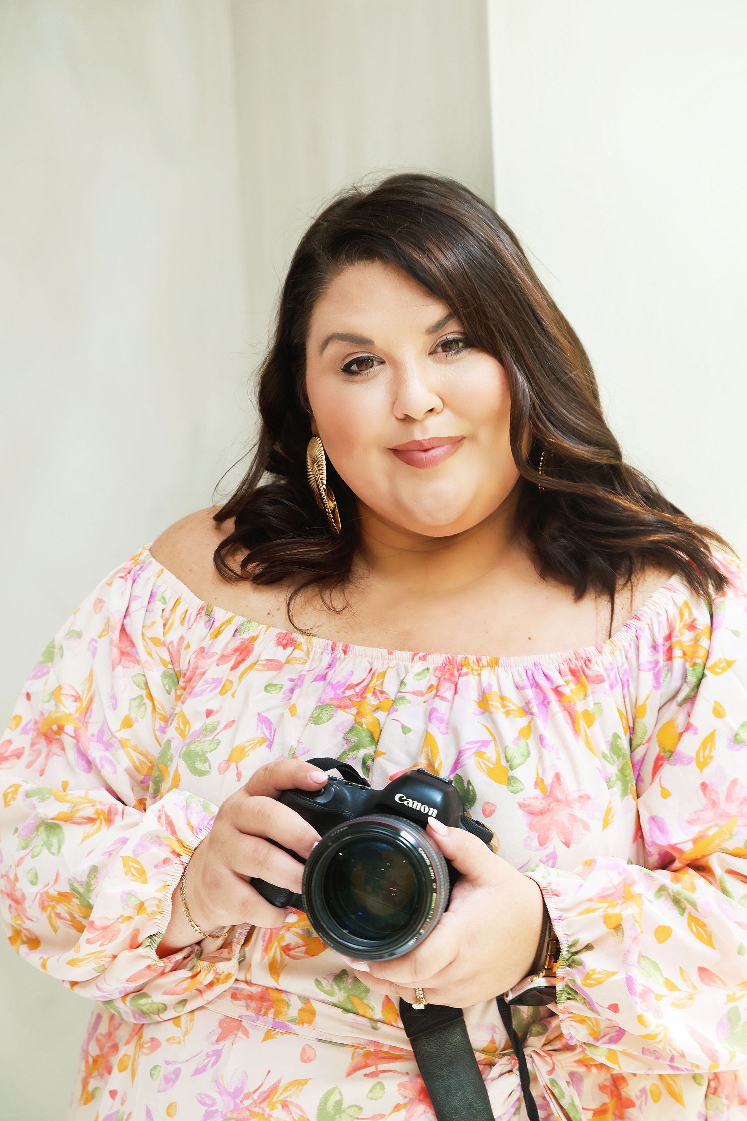 Studio portrait featuring elegant makeup and a white patterned top with gold accents.