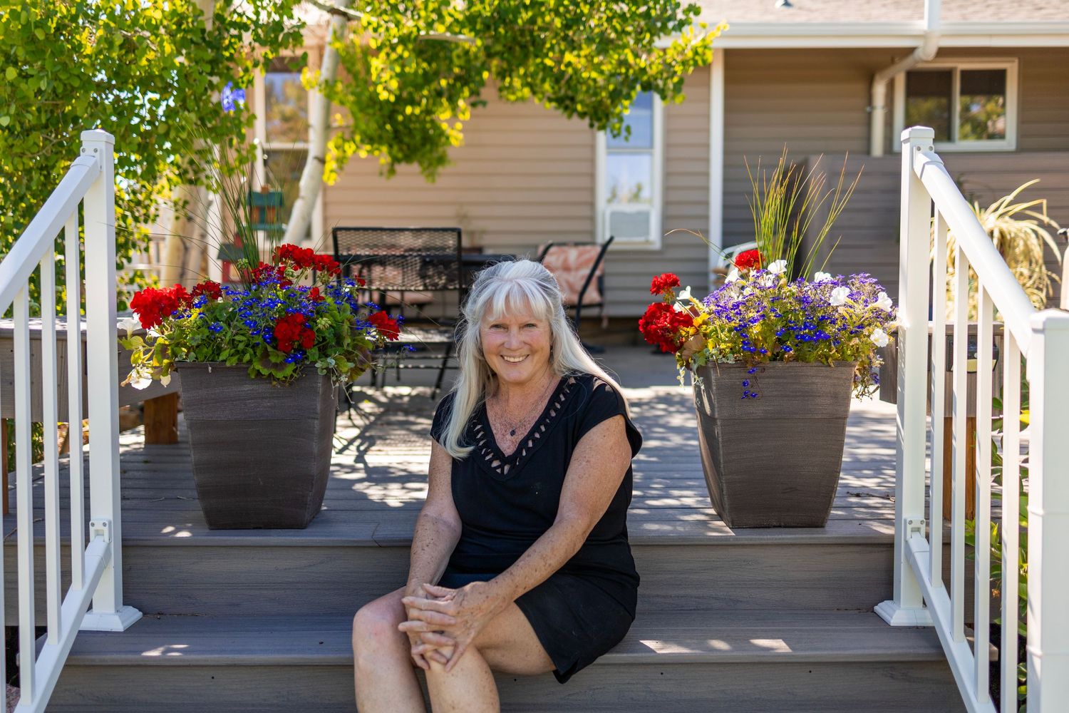 Front porch of a house decorated with colorful hanging flower baskets and outdoor furniture.