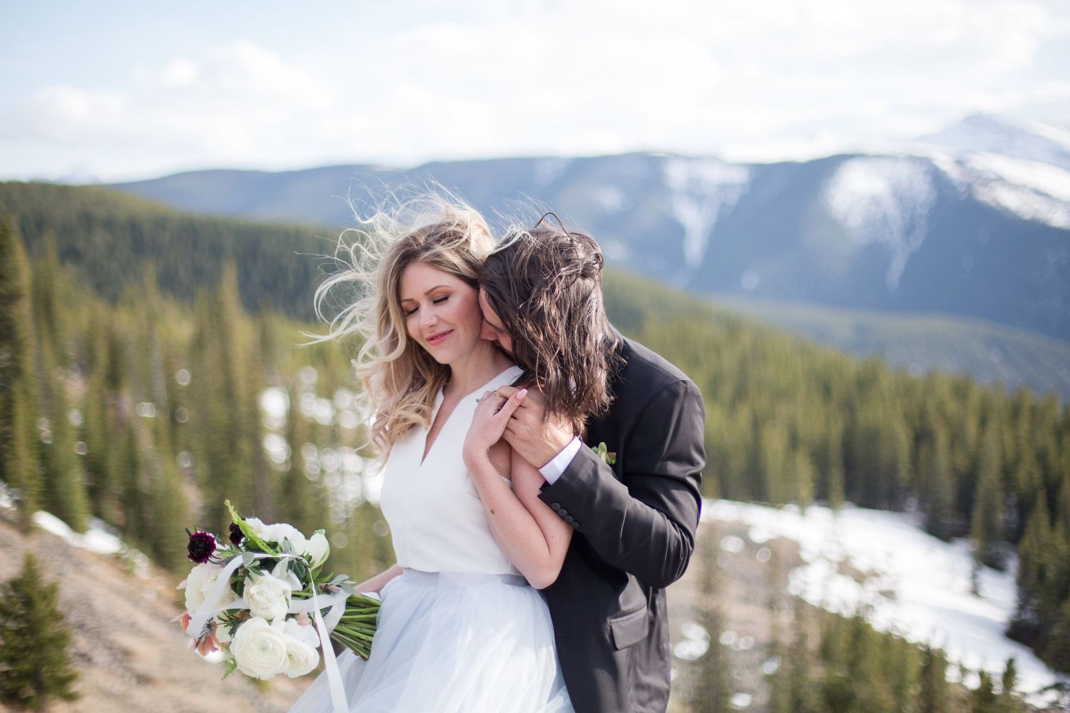 Romantic winter mountain wedding portrait with snow-capped peaks in background.