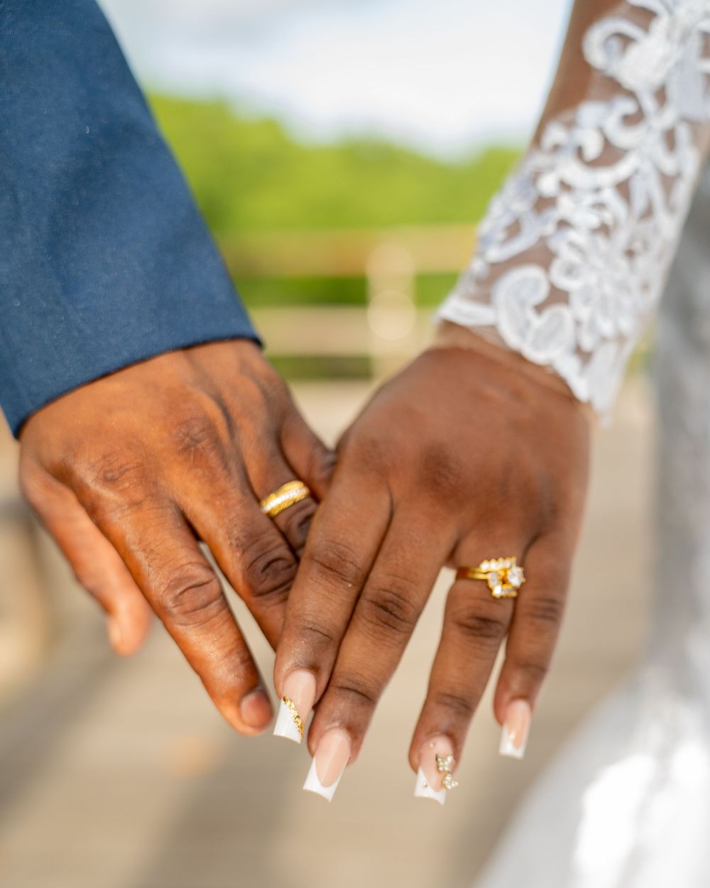 Close up of newlywed couple's hands showing wedding rings and bridal manicure.