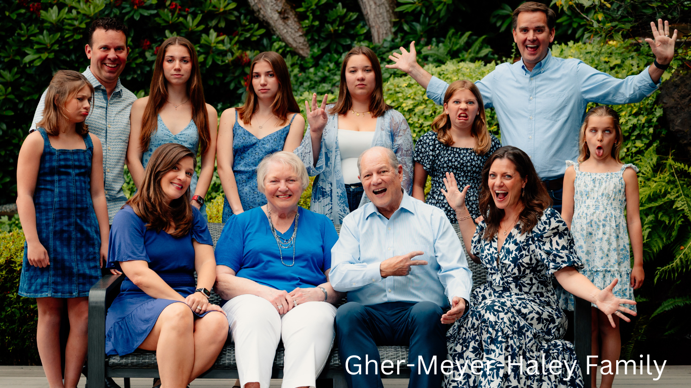 Multi-generational family portrait outdoors with everyone dressed in coordinating blue outfits.