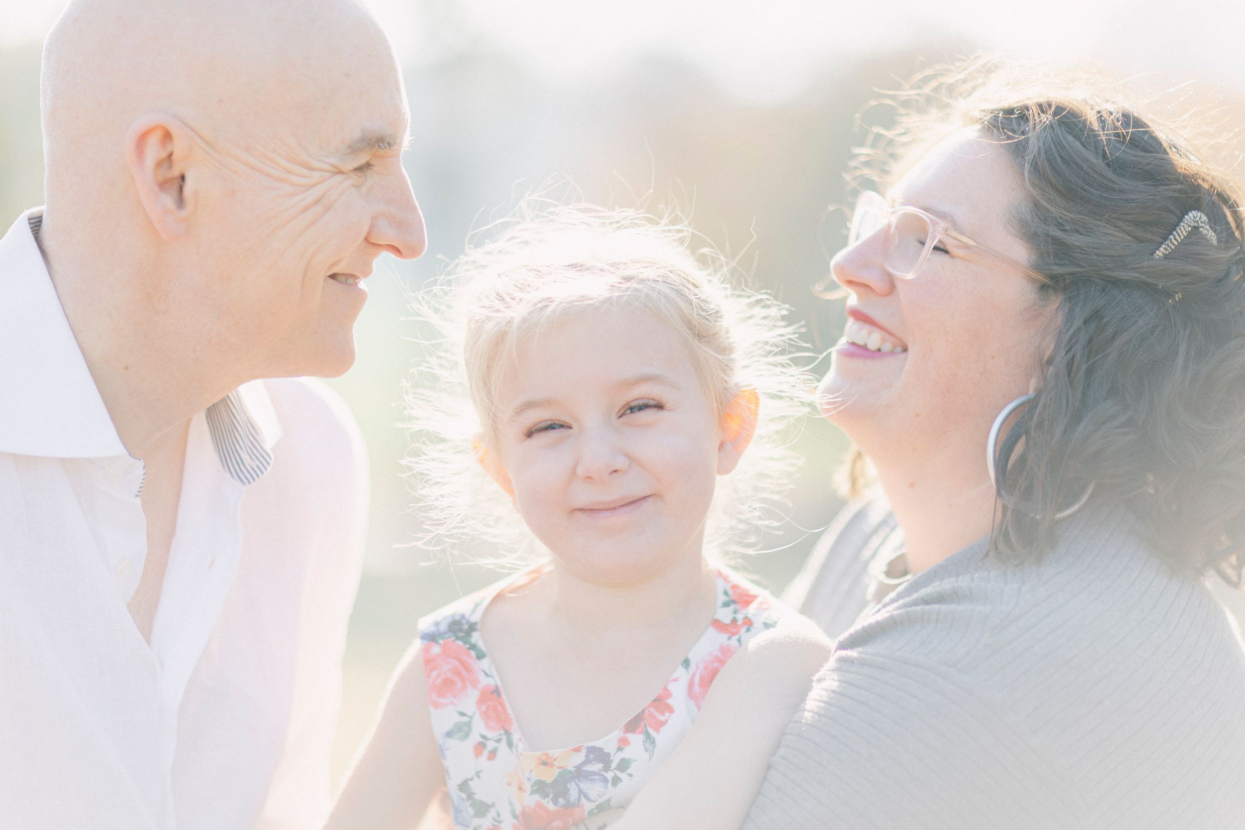 A family shares joyful laughter together in dreamy sunlit outdoor setting.