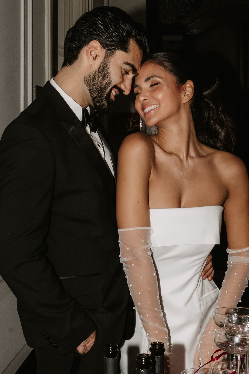 Newlyweds sharing intimate moment while standing by champagne display.