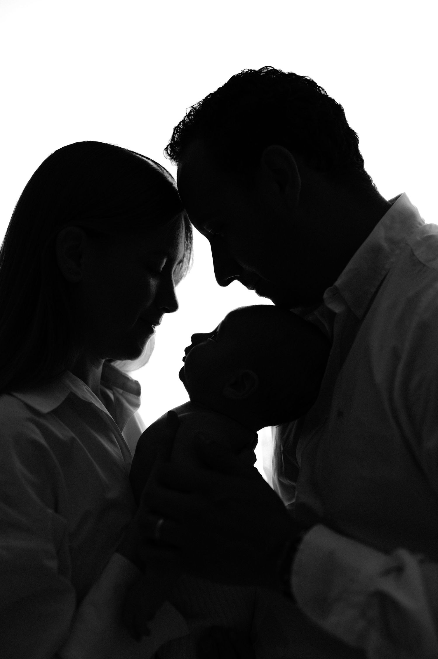 Silhouetted family portrait in dramatic backlighting showing intimate moment.