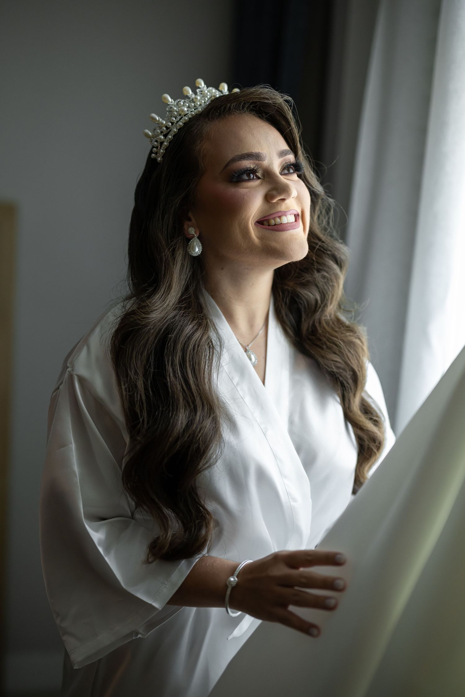 Elegant bridal preparation scene by window with white robe and crown.