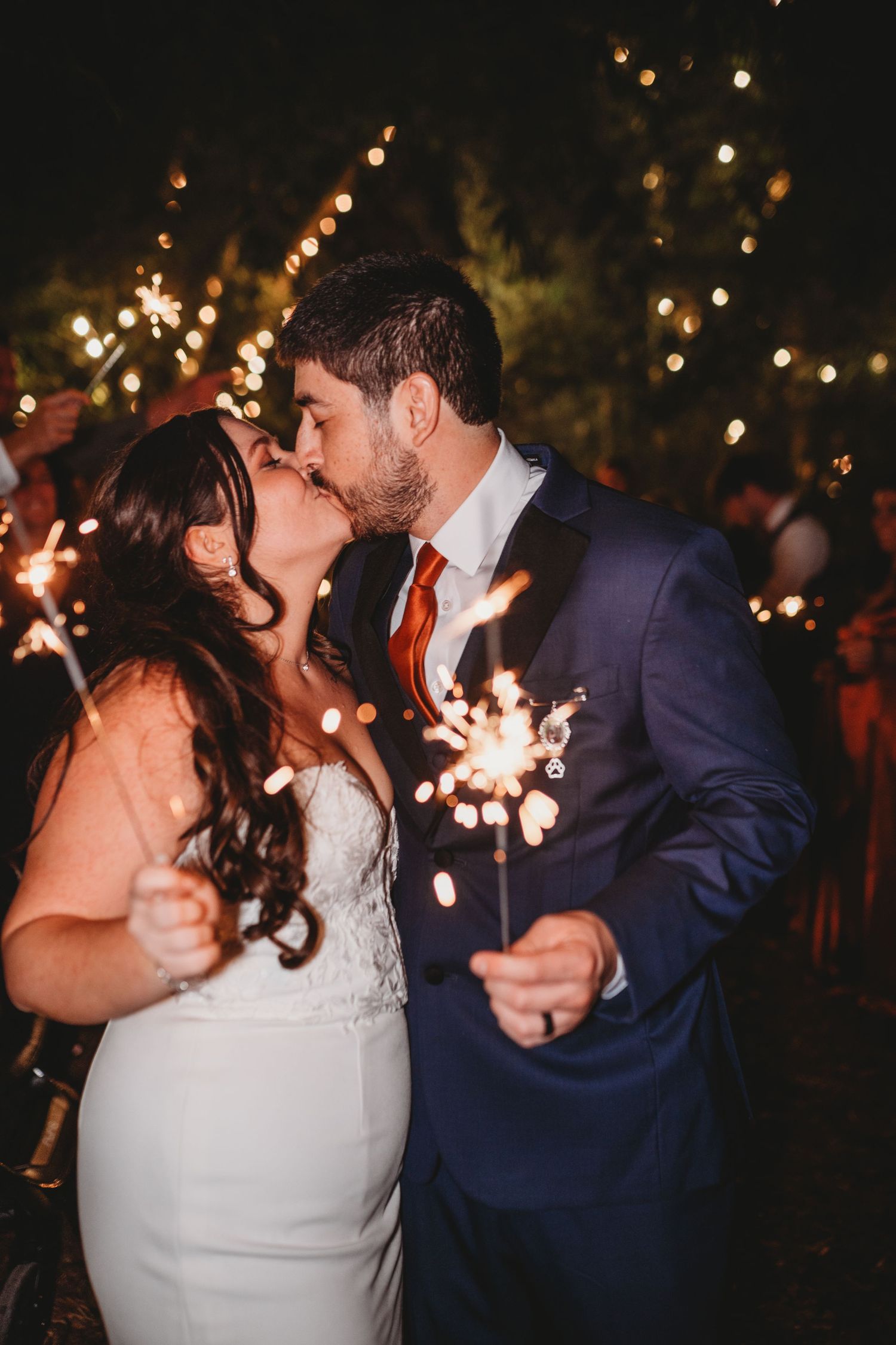 Couple sharing a romantic moment with sparklers during nighttime wedding celebration.