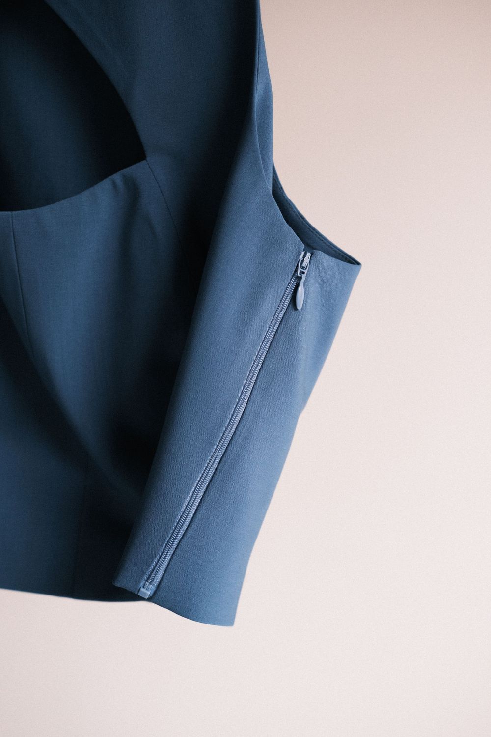 Close-up series showing sleeve detail of a navy blue blazer with button placket against white background.