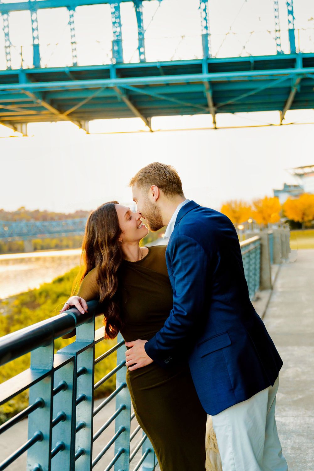 Liz and Chris's Engagement Downtown Cincinnati at Smale Park kissing with fall leaves and Roebling Bridge: Cincinnati Wedding Photographer