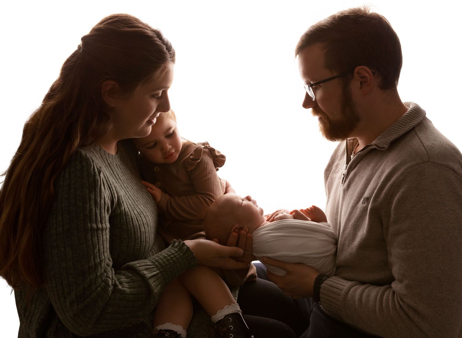 New Hampshire newborn photography of parents holding their baby, emotional lifestyle-inspired studio portrait celebrating family connection.