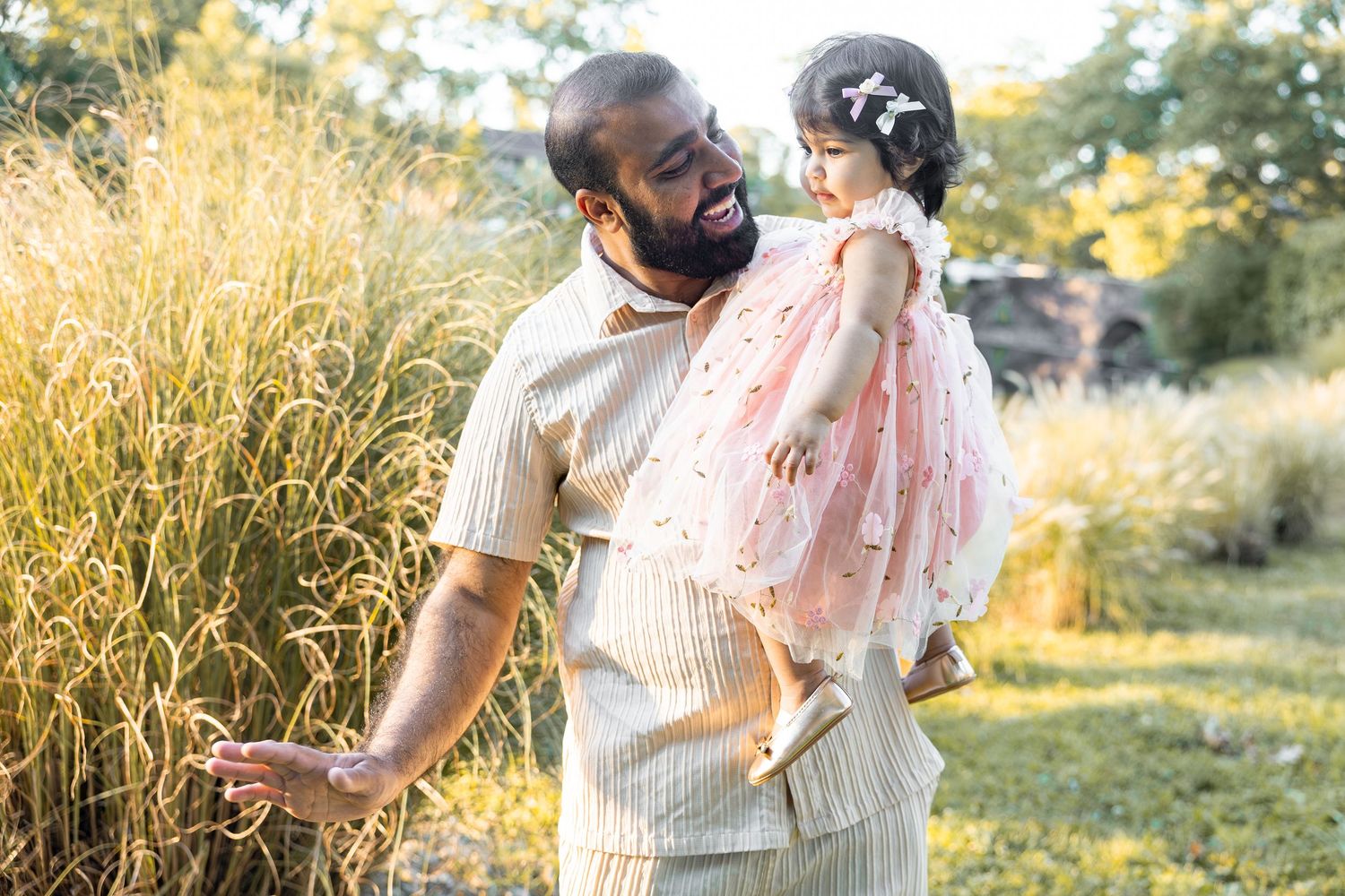 Couple shares joyful moments in golden sunlit field during outdoor photo session.
