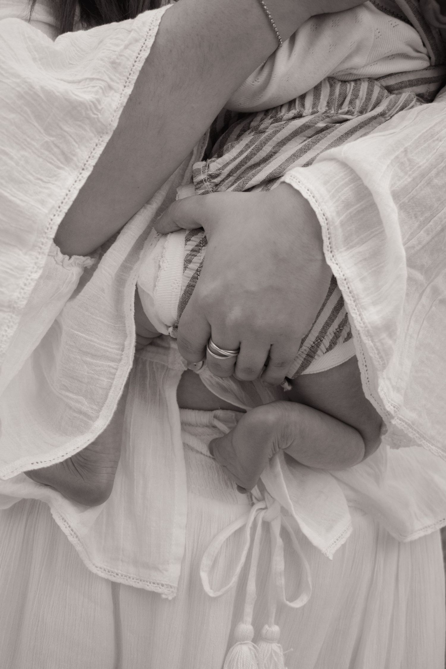 Mum picking up newborn baby, holding them close, newborn scrunch visible with tiny legs and feet. Newborn photoshoot Maitland NSW