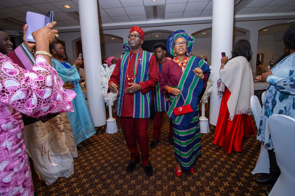 People gathered at a cultural celebration wearing traditional clothing and colorful garments in an indoor venue.