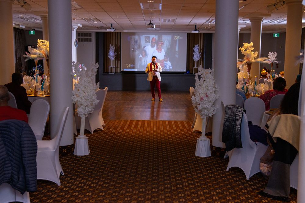 A panoramic view of a decorated wedding reception venue with white chairs and tables arranged in a banquet hall.
