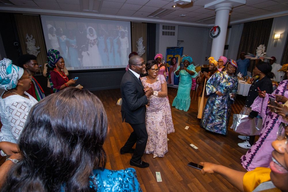 People dancing and enjoying themselves at a party in a dimly lit room with wood flooring.