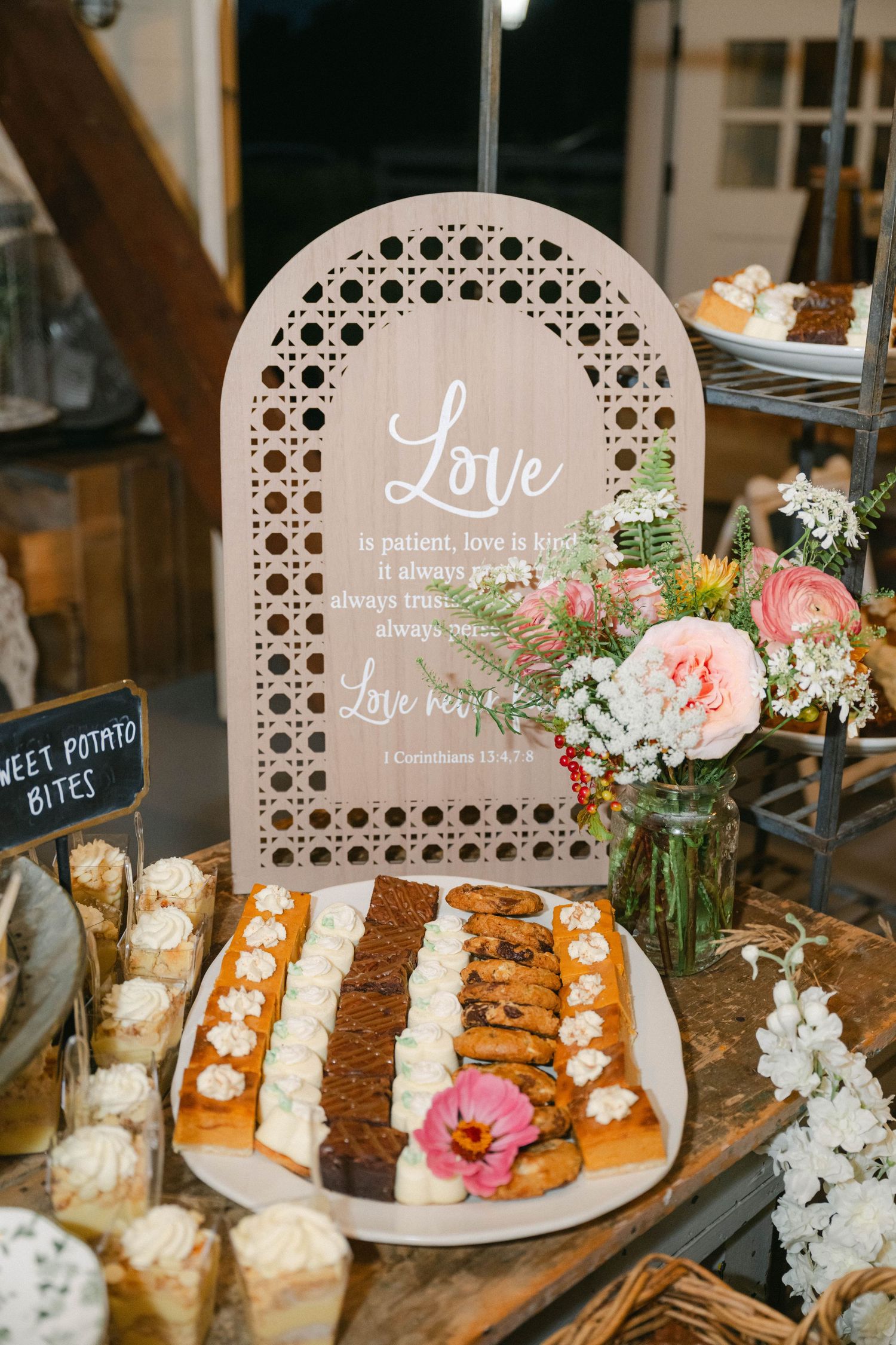 Rustic wedding dessert display with cupcakes and floral decorations arranged under wooden signs with love quotes. - Elawa Farm