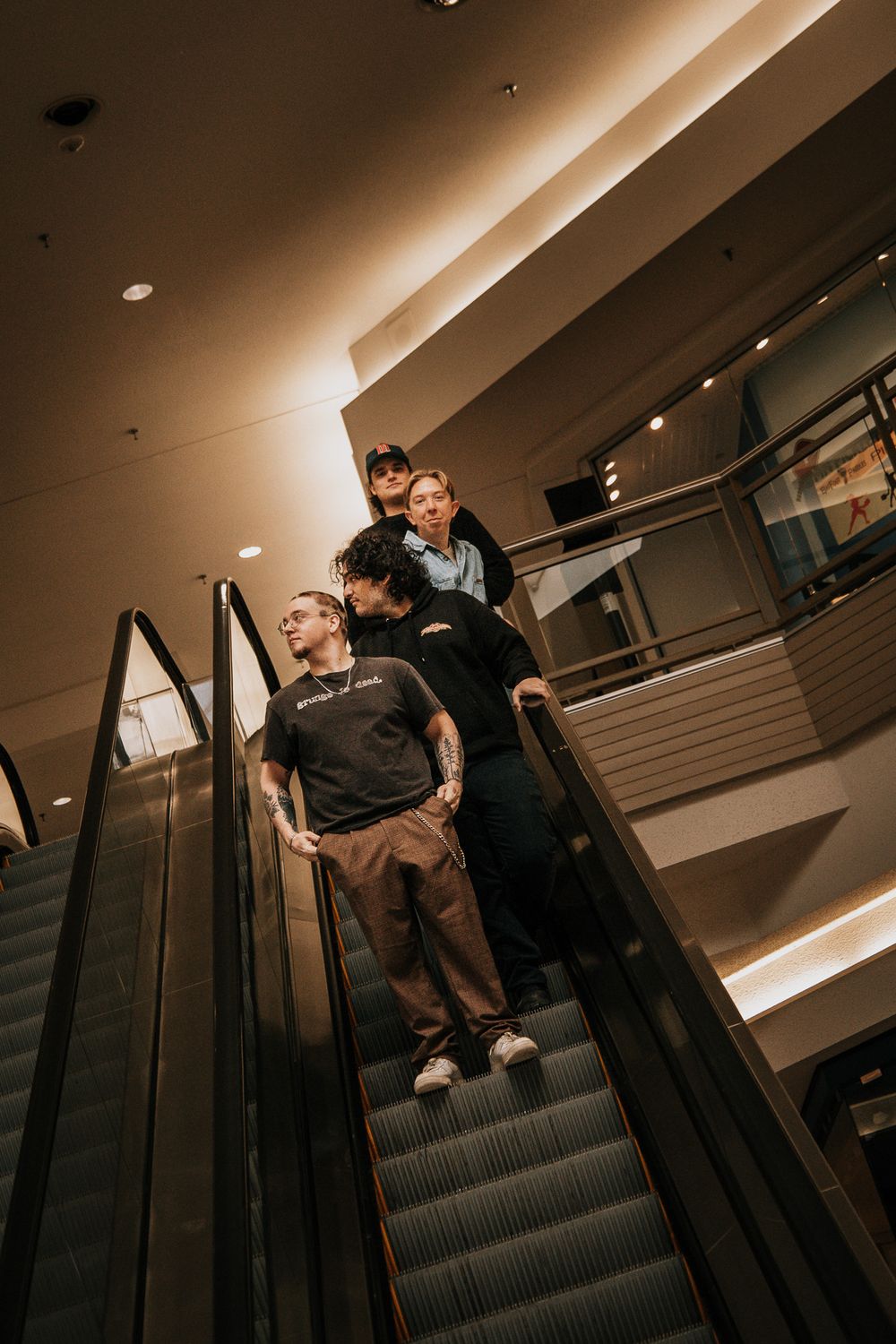 People riding an escalator in a modern shopping mall with warm ambient lighting and architectural details.