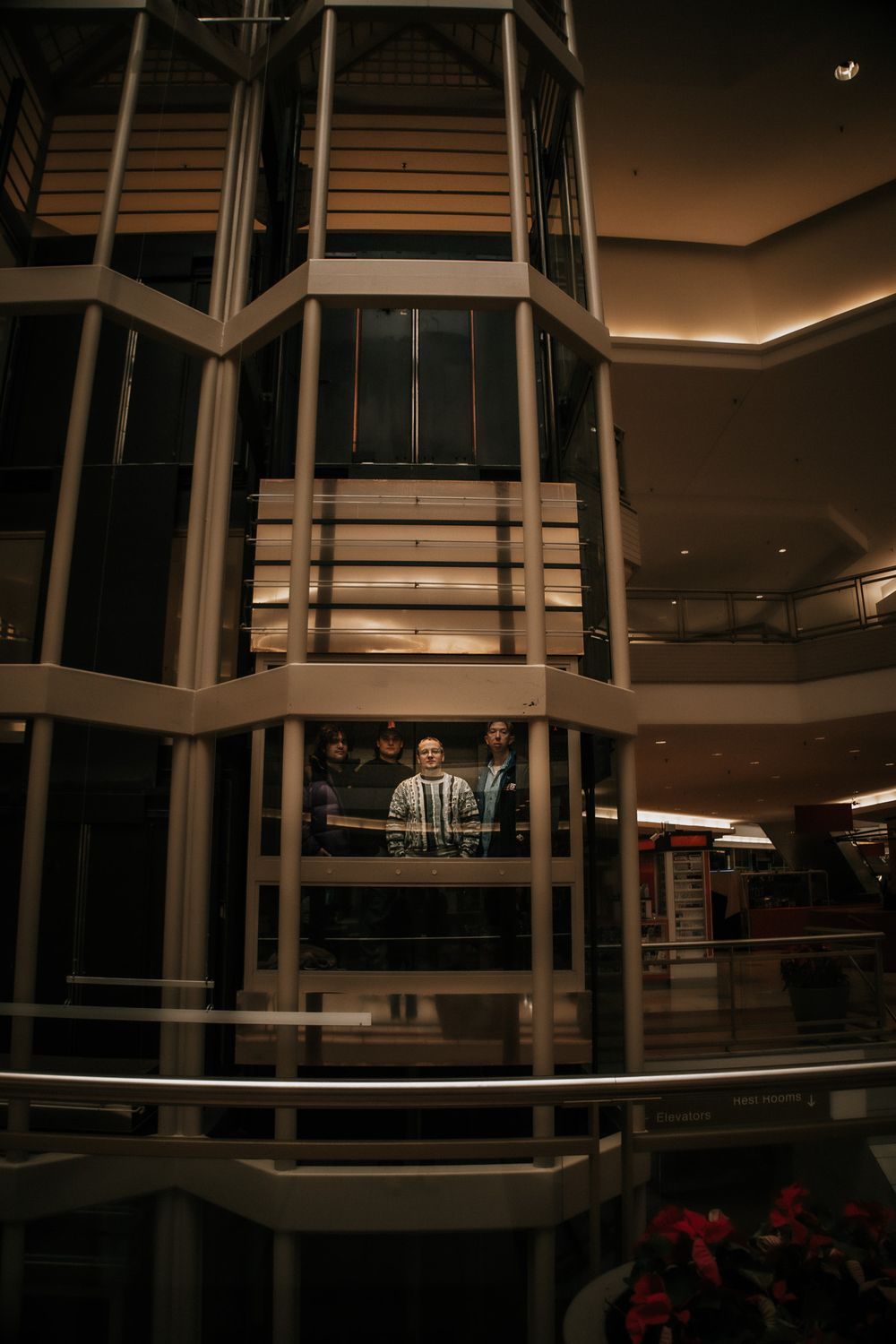 Modern glass elevator and architectural details in a shopping mall with warm lighting and decorative elements.