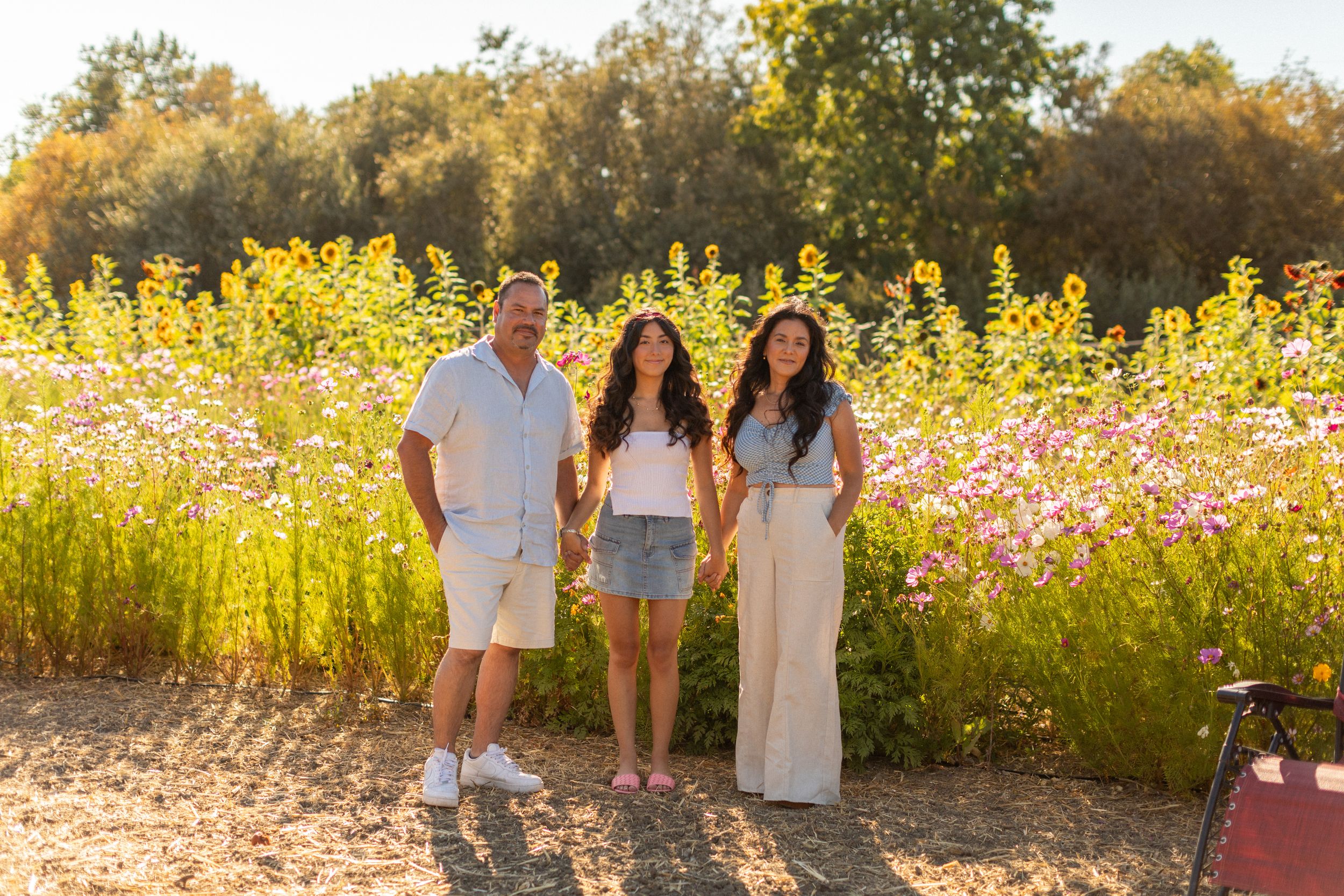 Golden sunlight illuminates people walking together in a wildflower field during sunset.