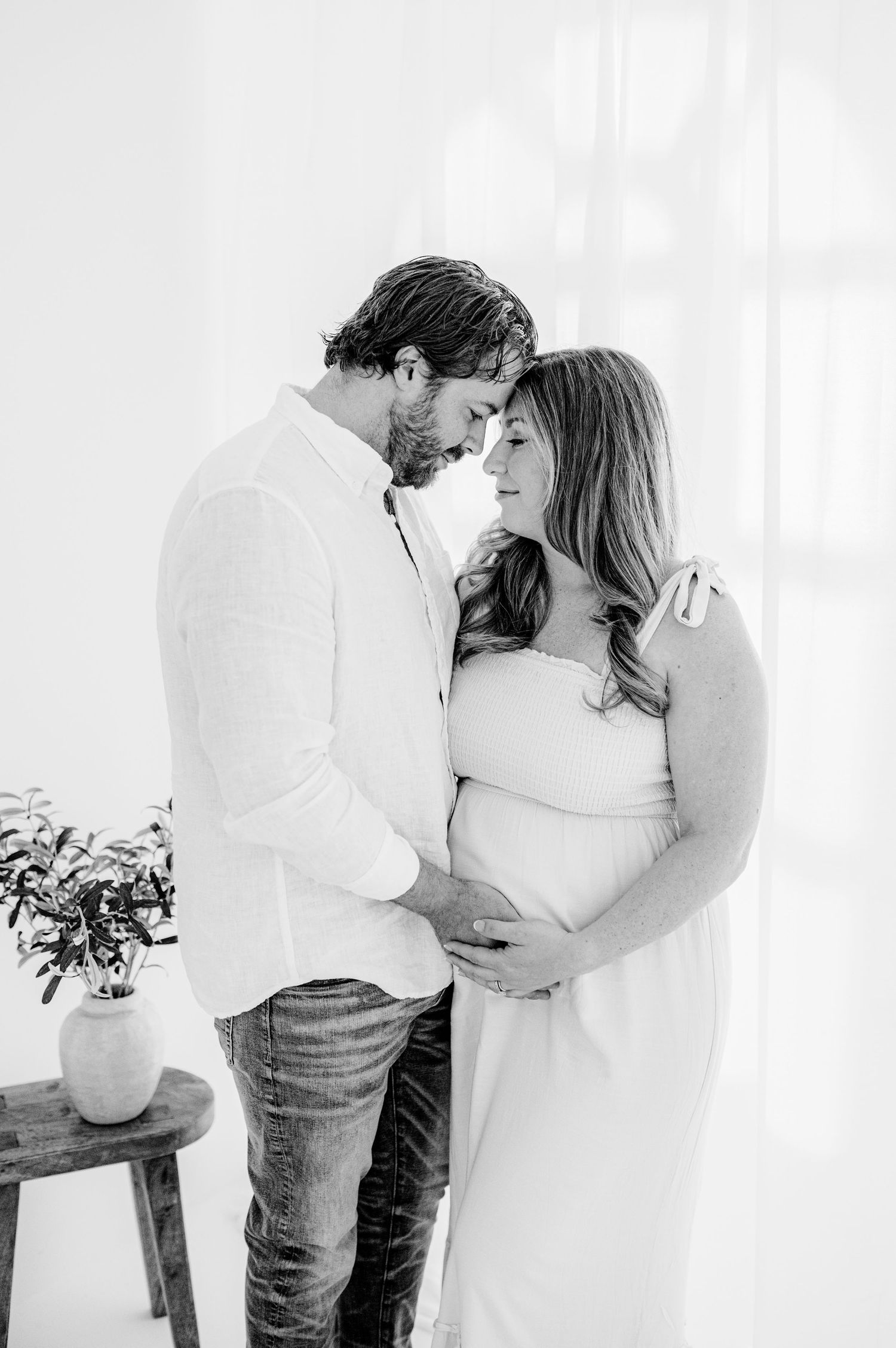 Black and white photo showing tender moments between a couple in a minimalist setting during Jacksonville, Fl maternity photography session