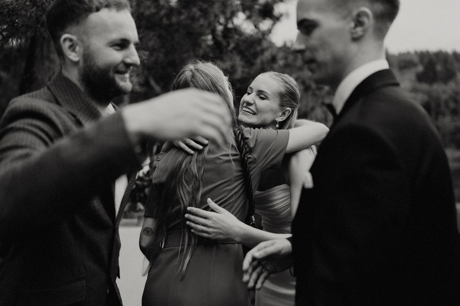 Candid black and white shots of guests embracing during a celebration.