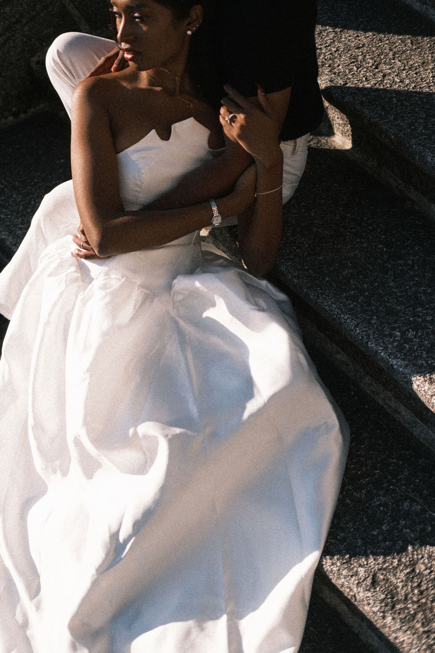 Close-up details of a white wedding dress flowing across dark stone steps in dramatic lighting.
