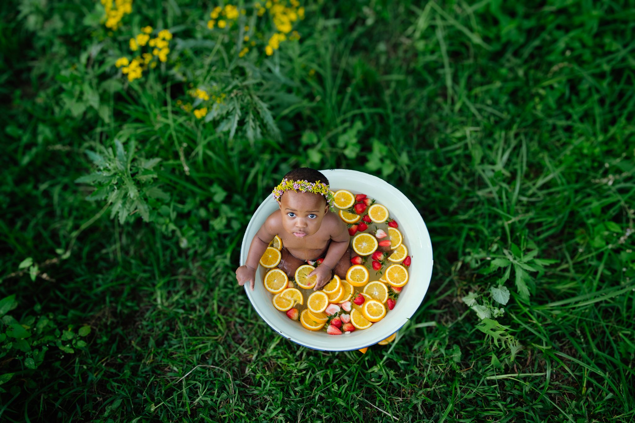 Bird’s-eye view of a one-year-old girl in a forest fruit bath