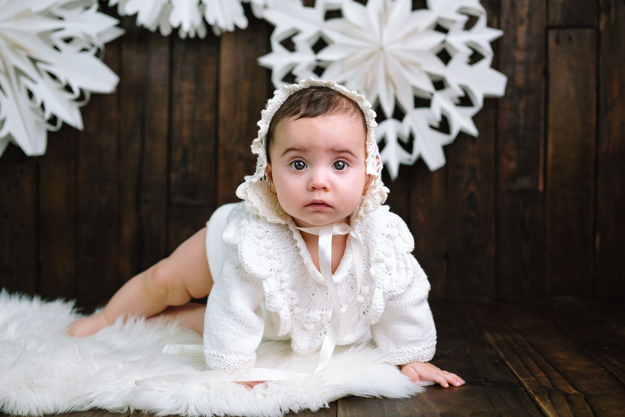 Nine-month-old baby in a vintage outfit with a snowflake studio backdrop