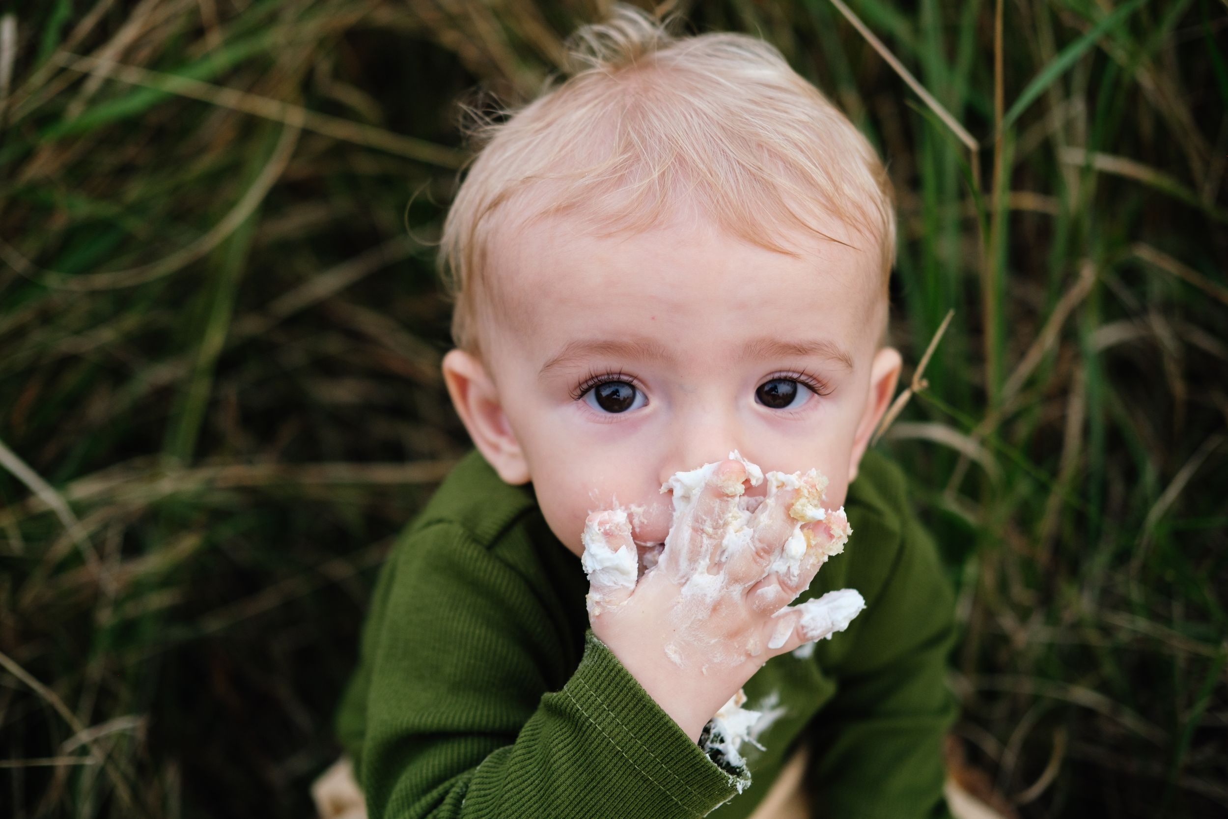 One-year-old baby enjoying a cake smash and eating birthday cake