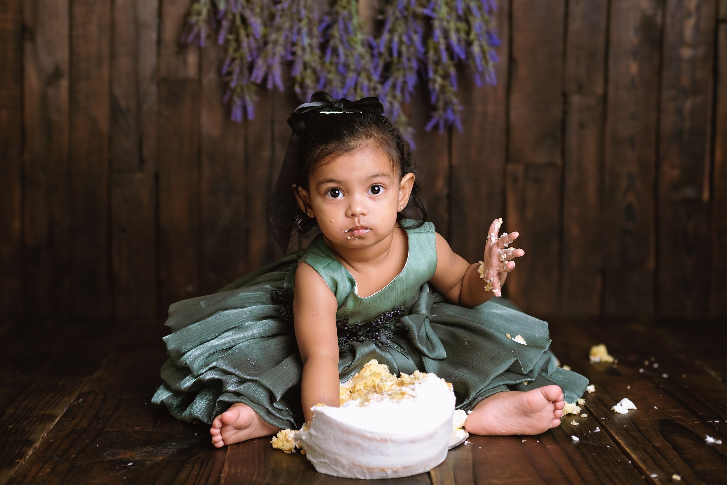 One-year-old girl smashing a birthday cake during a studio photoshoot