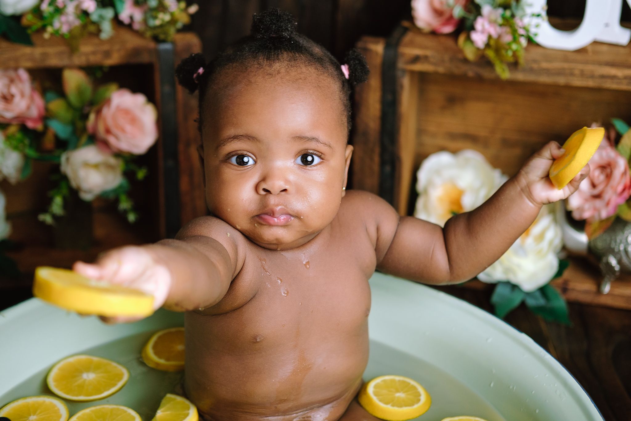 One-year-old studio cake smash offering a lemon to the camera