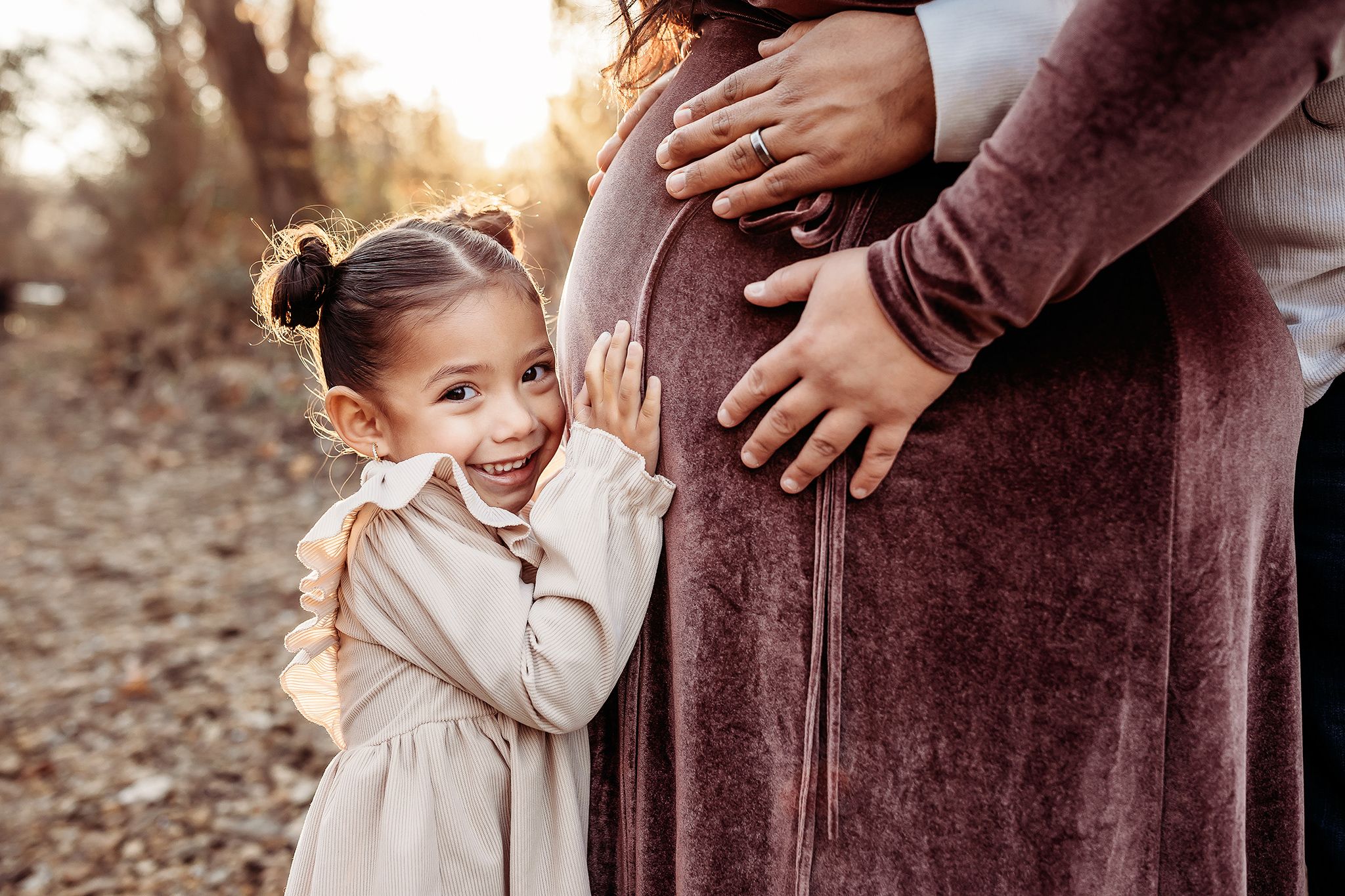 A tender moment between parent and child captured during golden hour in a natural outdoor setting.