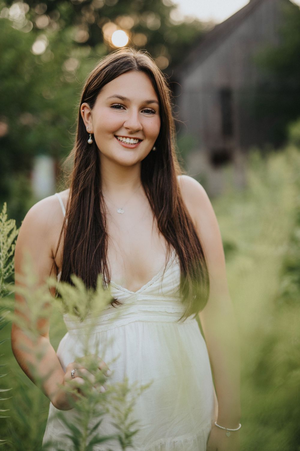 Portrait session in lush green outdoor setting with white summer dress and natural lighting.