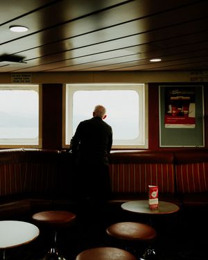 Dark interior of a diner booth with silhouetted figures and windows creating dramatic lighting and shadows.