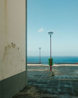 A series of minimalist coastal images showing lamp posts against a blue sky and ocean horizon in a geometric composition.