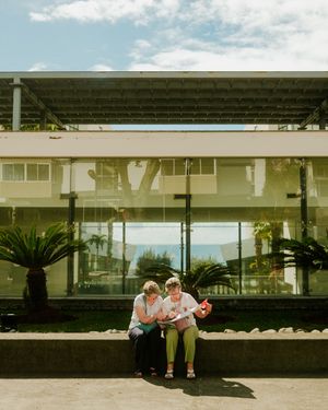 Long modernist building with glass windows and covered patio area overlooking a scenic landscape.
