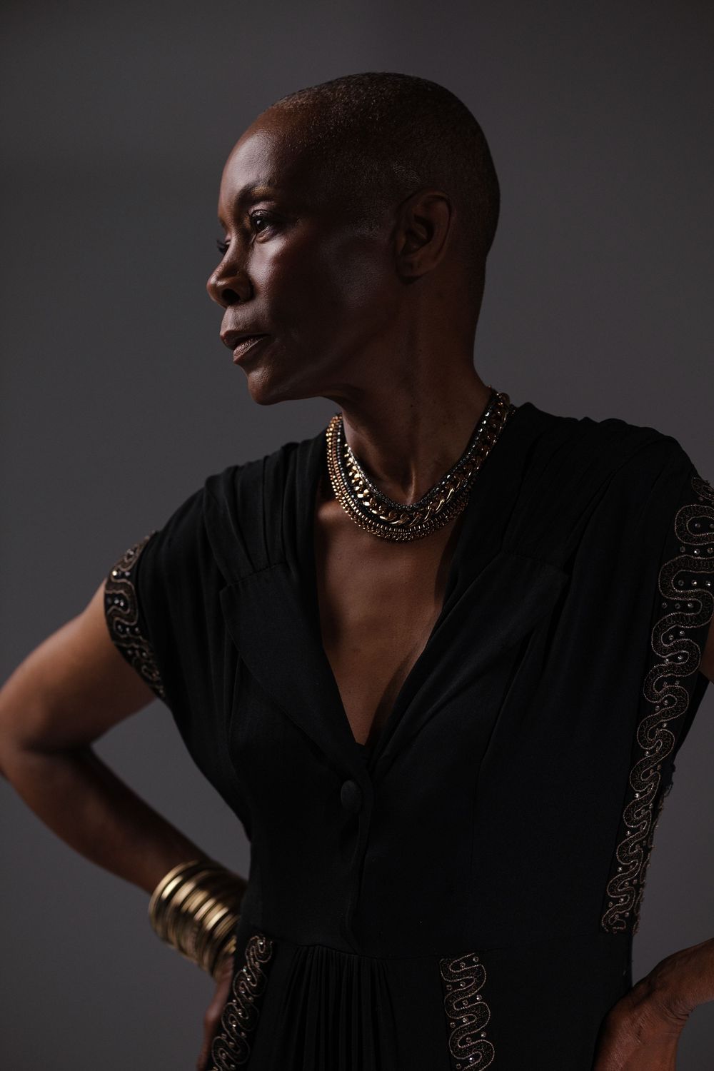 Artistic portrait series featuring gold jewelry and a black v-neck dress in moody lighting.