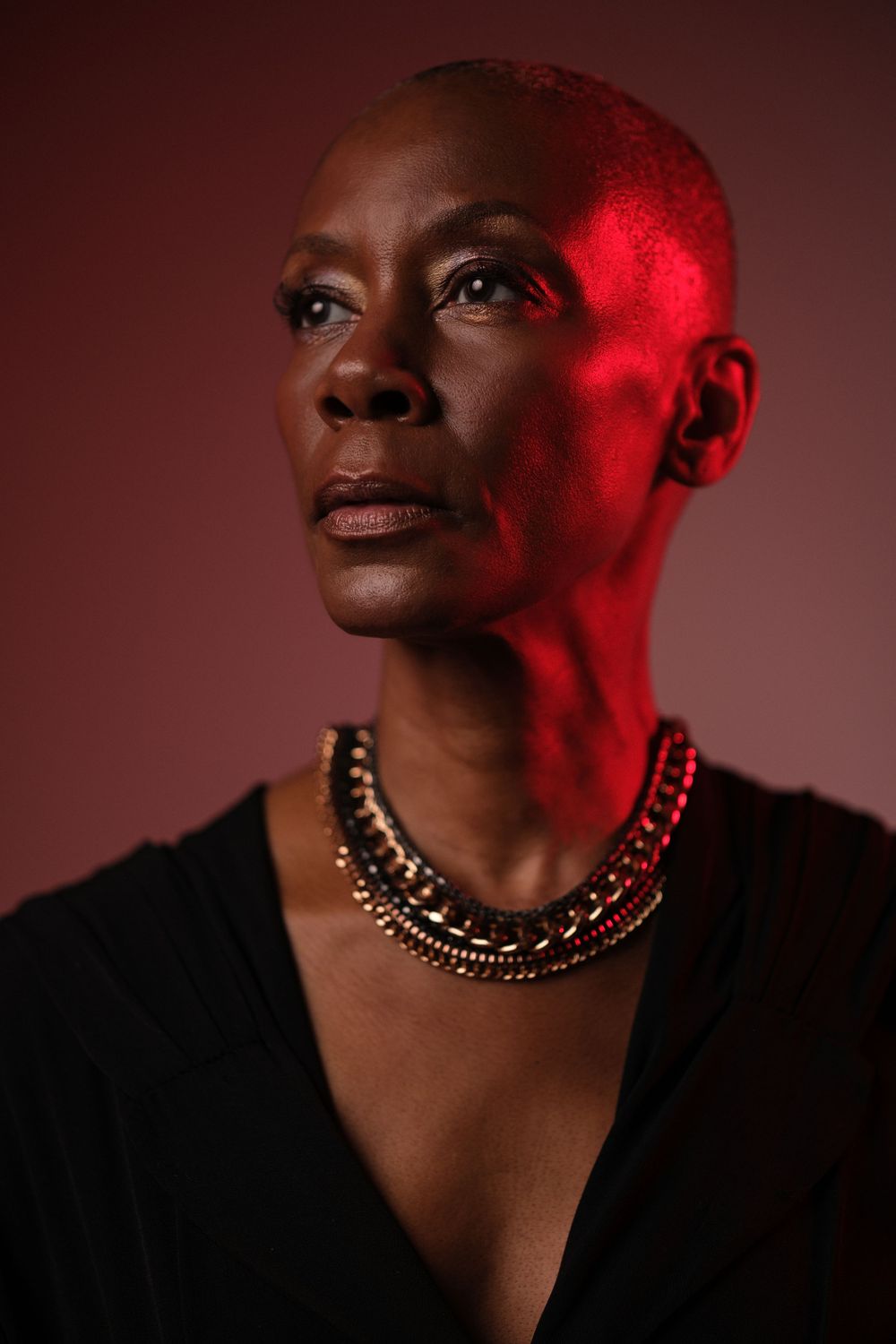 Close-up portraits with red lighting highlighting gold necklace and dramatic expressions.