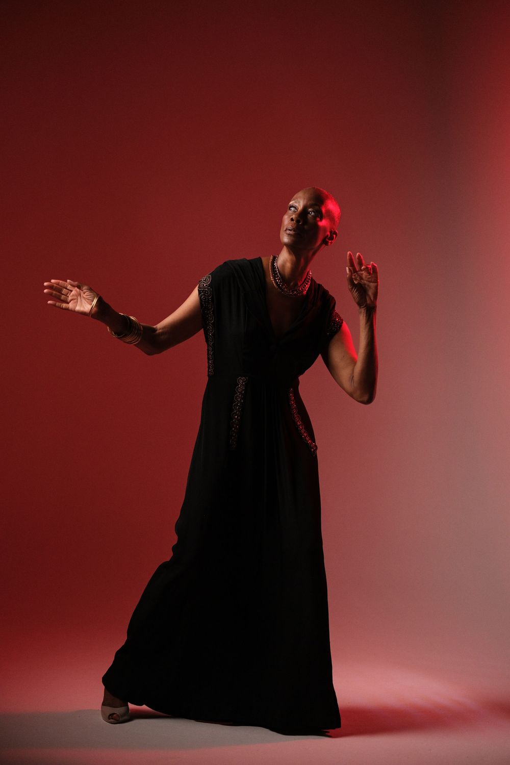 Dynamic movement series showing flowing black dress against dramatic red backdrop.