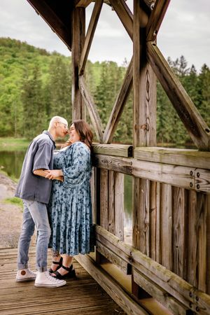 Romantic couple sharing intimate moment on rustic wooden covered bridge.